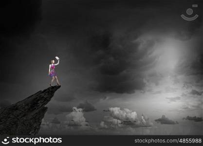 More colors. Young girl in multicolored bright dress on rock top