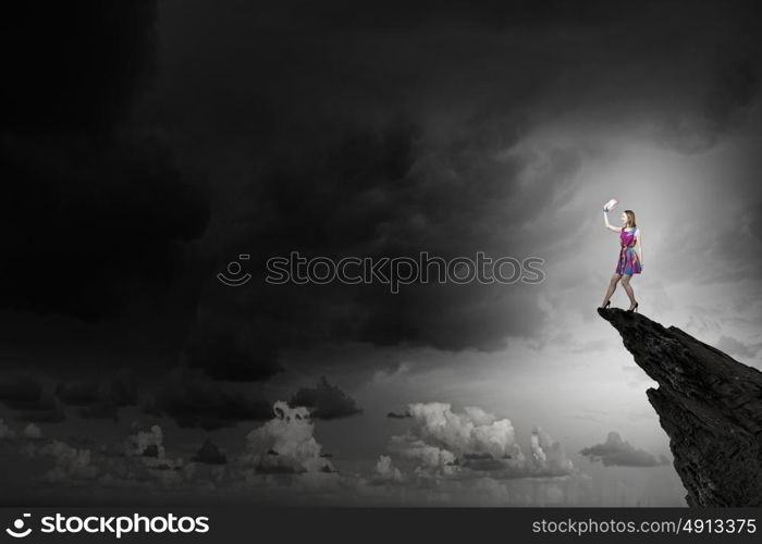 More colors. Young girl in multicolored bright dress on rock top