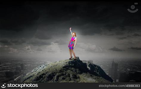 More colors. Young girl in multicolored bright dress on rock top