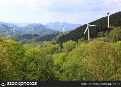 more wind turbines in the mountains on the horizon line on cloudy sky background