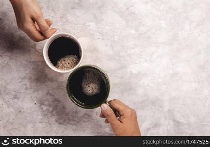 Moring Drink Concept. Couple or Two Friends holding a Cup of Coffee to making Cheers in Cafe or Restaurant . Top View on Table