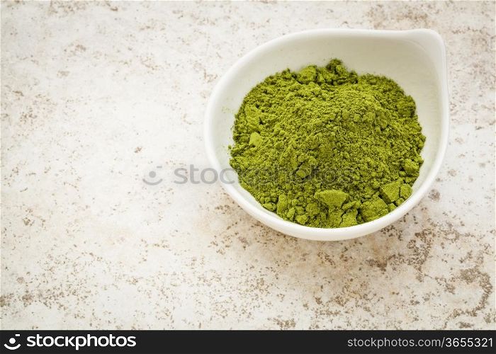 moringa leaf powder in a small bowl against a ceramic tile background