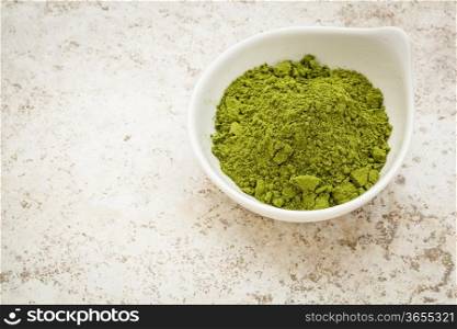 moringa leaf powder in a small bowl against a ceramic tile background