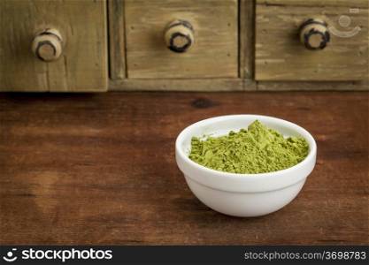 moringa leaf powder in a small bowl with a rustic drawer cabinet
