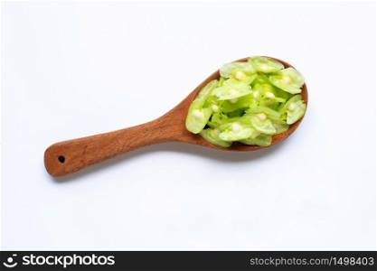 Moringa oleifera seeds on wooden spoon isolated on white background.