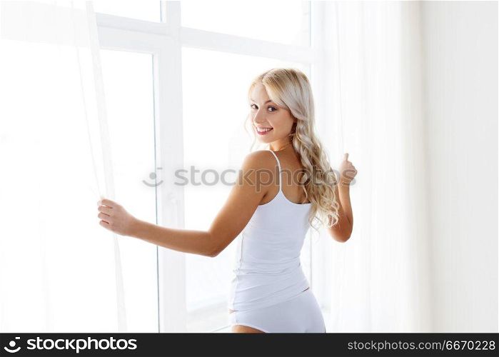 morning and people concept - beautiful young woman in white underwear at window. woman in underwear at window in morning. woman in underwear at window in morning