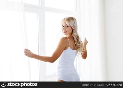 morning and people concept - beautiful young woman in white underwear at window. woman in underwear at window in morning. woman in underwear at window in morning