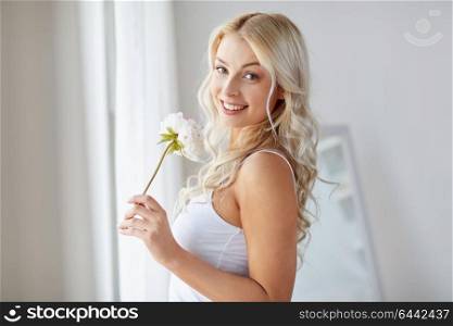 morning and people concept - beautiful young woman in white underwear smelling peony flower at home window. woman in underwear smelling flower at window