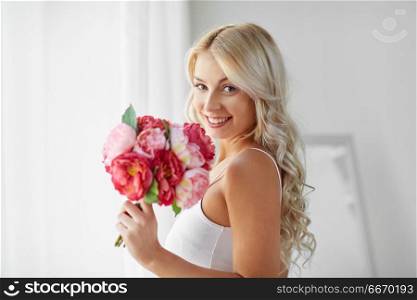 morning and people concept - beautiful young woman in white underwear with bunch of flowers at home window. woman in underwear with bunch of flowers at window. woman in underwear with bunch of flowers at window