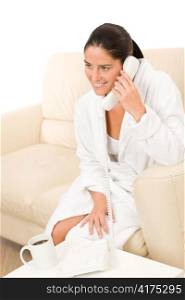 Morning attractive mid-aged woman speaking on phone wearing bathrobe