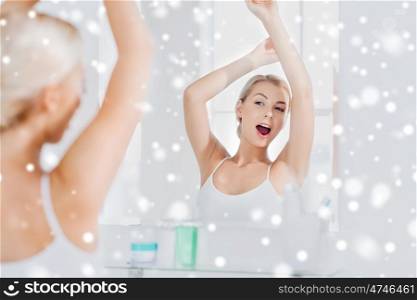 morning, awakening and people concept - sleepy young woman yawning and stretching in front of mirror at bathroom over snow