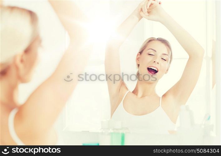 morning, awakening, morning and people concept - sleepy young woman yawning and stretching in front of mirror at bathroom. woman yawning in front of mirror at bathroom. woman yawning in front of mirror at bathroom