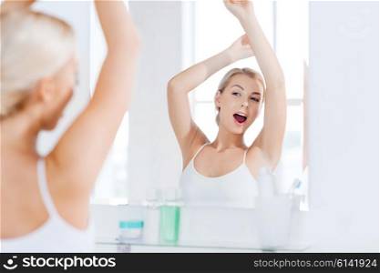 morning, awakening, morning and people concept - sleepy young woman yawning and stretching in front of mirror at bathroom