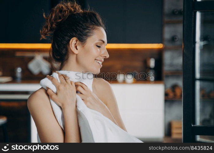 Morning beauty routine. European girl is wiping face with soft towel after washing. Happy young woman takes shower at home and doing skin care. Hygiene, dermatology and spa procedures.. Morning beauty routine. Happy european girl is wiping face with soft towel after washing.