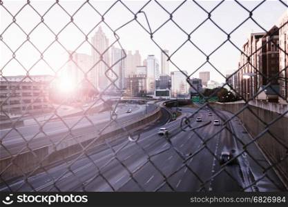 Morning city skyline through the wire mesh fence. Sunrise Atlanta cityscape, Georgia, USA