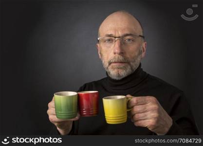 Morning coffee anybody? 60 years old bald man with a beard and glasses carrying three espresso coffee cups - a headshot against a black background