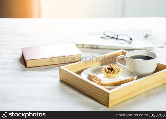 Morning coffee bread and book or newspaper on the bed . Morning coffee bread and book or newspaper on the bed.