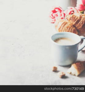 Morning coffee, croissants and spring tulips on light grey background, breakfast concept