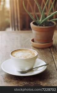 Morning coffee cup latte hot drink on rustic wood table background with small potted cactus succulent plant Aloe vera.