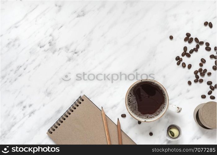 Morning composition with a cup of black coffee and a notebook on a marble surface with space for text, top view