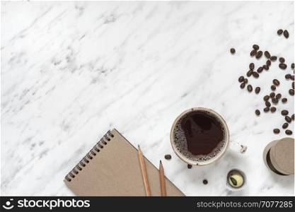 Morning composition with a cup of black coffee and a notebook on a marble surface with space for text, top view