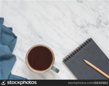 Morning composition with cup of black coffee, blue napkin and notebook on a marble surface, with space for text, top view