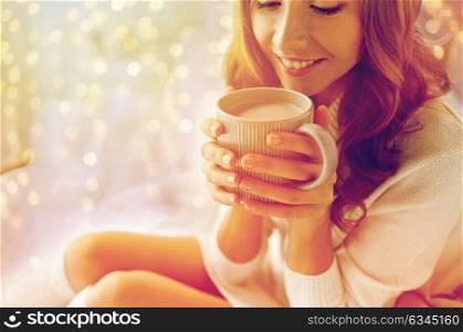 morning, coziness, winter and people concept - close up of happy young woman with cup of coffee or cacao in bed at home. close up of happy woman with cocoa cup at home
