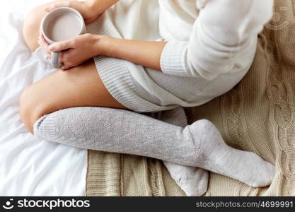 morning, coziness, winter and people concept - close up of young woman with cup of coffee or cacao in bed at home