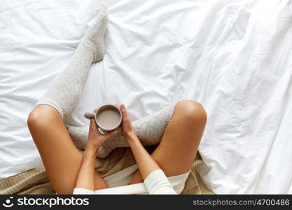 morning, coziness, winter and people concept - close up of young woman with cup of coffee or cacao in bed at home