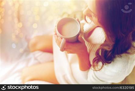 morning, coziness, winter and people concept - close up of young woman with cup of coffee or cacao in bed at home. close up of woman with cocoa cup in bed at home