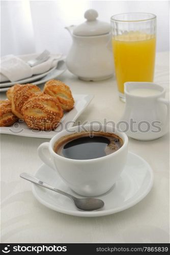 Morning cup of coffee with freshly baked rolls with sesame seeds, juice and milk