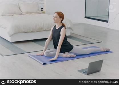 Morning exercises. Young caucasian woman is stretching on mat. Concept of internet learning and home classes. Personal training and gymnastics on quarantine. Home isolation.. Young caucasian woman stretching and doing morning exercises. Home isolation and internet learning.
