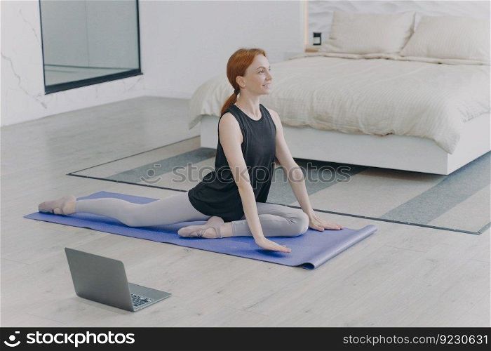 Morning exercises. Young caucasian woman is stretching on mat. Concept of internet learning and home classes. Personal training and gymnastics on quarantine. Home isolation.. Young caucasian woman stretching and doing morning exercises. Home isolation and internet learning.