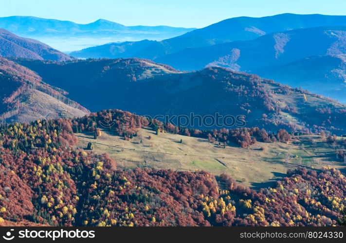 Morning fog in autumn Carpathian and colorful forest on slope.