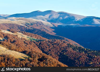Morning in autumn Carpathian. Mountain top daybreak landscape with colorful trees on slope.