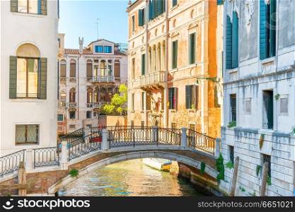 Morning in Venice street with canal, bridge, boats and gondolas