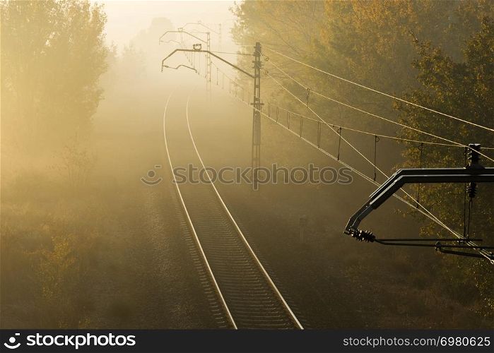 Morning landscape with train track through the fog.