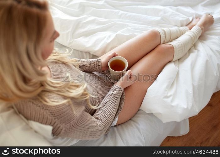 morning, leisure and people concept - close up of young woman with cup of tea in bed at home bedroom