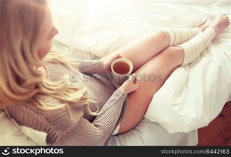 morning, leisure and people concept - close up of young woman with cup of tea in bed at home bedroom. close up of woman with tea cup in bed
