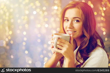 morning, leisure, christmas, winter and people concept - happy young woman with cup of coffee or tea at home. happy woman with cup of tea or coffee at home