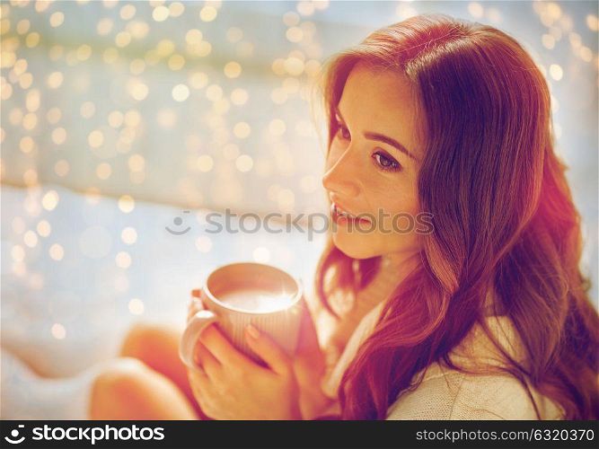 morning, leisure, winter and people concept - happy young woman with cup of coffee or cocoa in bed at home. happy woman with cup of cocoa in bed at home