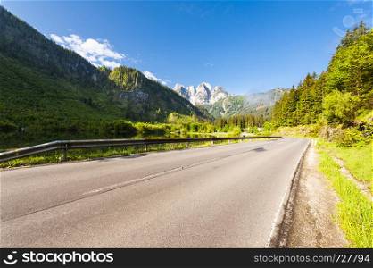 Morning mist over asphalt road in Austrian landscape with forests, fields, pastures and meadows