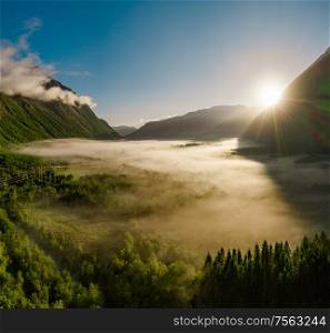 Morning mist over the valley among the mountains in the sunlight. Fog and Beautiful nature of Norway aerial footage.