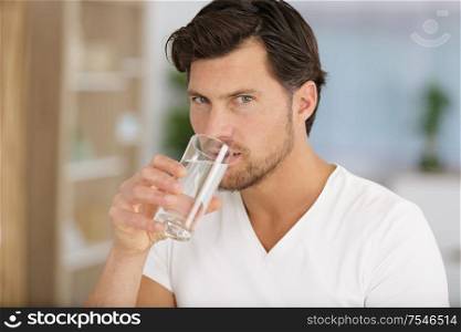 morning of handsome young man drinking water at home