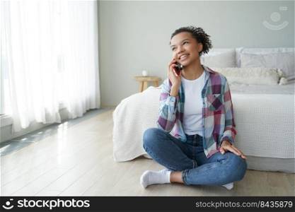 Morning phone call. Young african american woman is talking to friend on smartphone in bedroom. Cute spanish teenage girl in casual wear is phone addict. Communication and relaxation.. Morning phone call. Teenage girl in in casual wear is talking to friend on smartphone in bedroom.