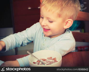 Morning routine in family, healthy diet for children concept. Kid boy eating breakfast, cereals and milk. Kid boy eating breakfast, cereals and milk in bowl