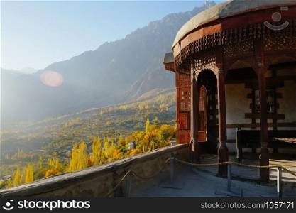 Morning sunlight lit colorful forest trees in Hunza valley against Karakoram mountain range in the background. View from ancient Baltit fort. Autumn season in Gilgit Baltistan, northern Pakistan.