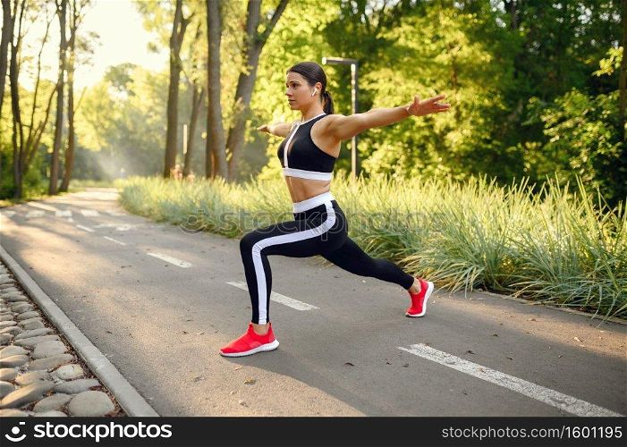 Morning training in summer park, woman doing stretching exercise. Female runner goes in for sports at sunny day, healthy lifestyle, jogger on outdoors workout. Morning training in park, stretching exercise