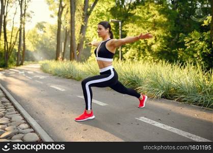 Morning training in summer park, woman doing stretching exercise. Female runner goes in for sports at sunny day, healthy lifestyle, jogger on outdoors workout. Morning training in park, stretching exercise