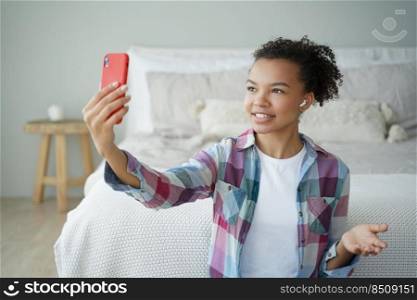Morning video phone call. Young african american woman is talking to friend on smartphone in bedroom. Teenage girl is holding smartphone and speaking in front of camera. Phone addiction concept.. Video phone call. Young african american woman is talking to friend on smartphone in bedroom.